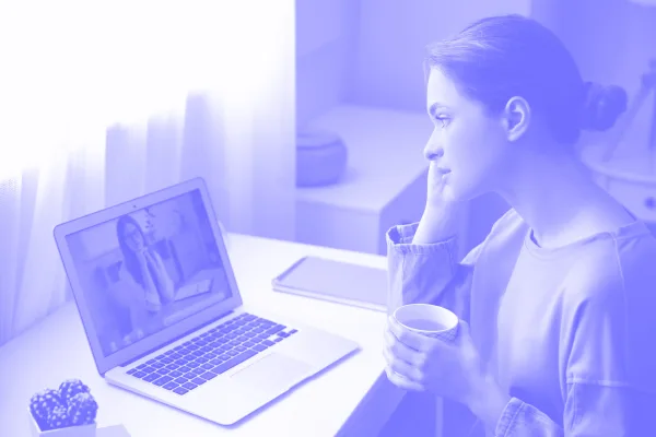 a woman holding a cup and looking at a laptop - psicologia online