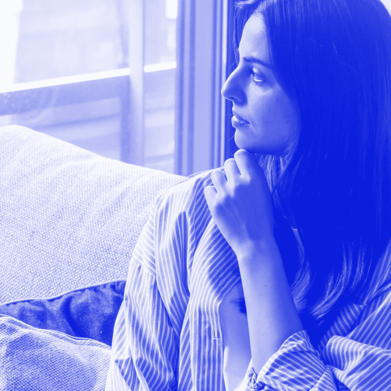 a woman sitting on a couch looking out a window